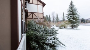 Un edificio con fachada marrón y blanca, un paisaje cubierto de nieve y árboles de hoja perenne.