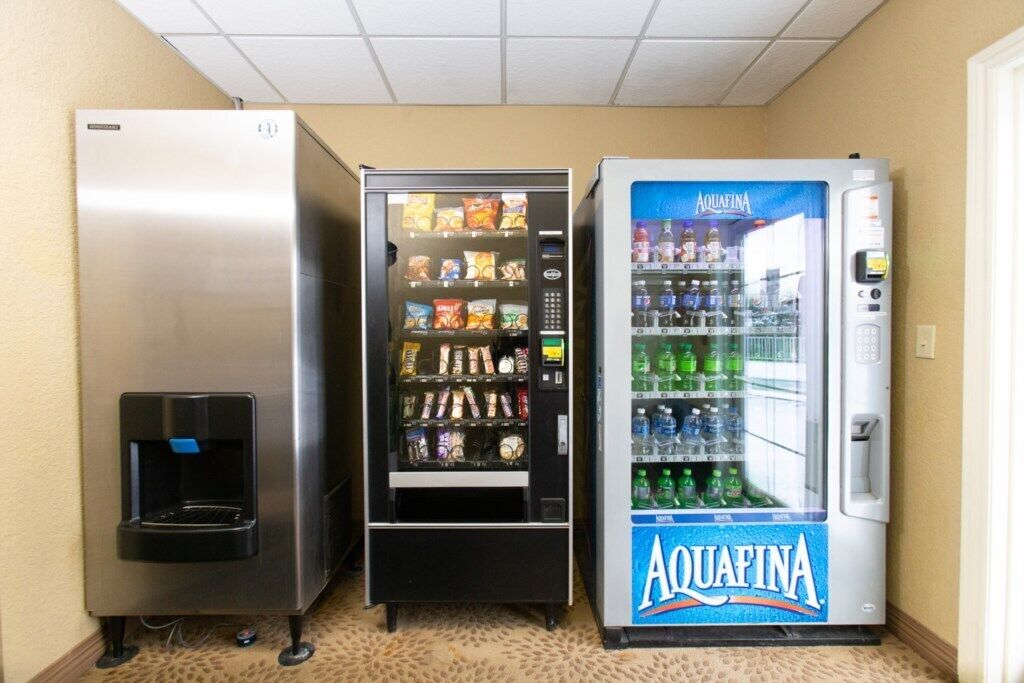 Three beverage vending machines in a hallway.