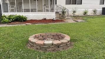 A house with a screened porch, a brick fire pit, and a well-maintained lawn.