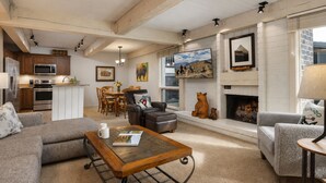 Una sala de estar con chimenea, un comedor y una cocina equipada con electrodomésticos modernos.