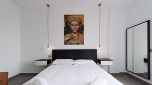 Ein modernes Hotelzimmer mit einem großen Bett, zwei Nachttischen, einem großen Spiegel und einem Bild an der Wand.