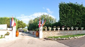 A gated entrance with flags, a stone wall, and potted plants.