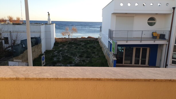 Un edificio con vista al mar, un pequeño jardín y una puerta azul.