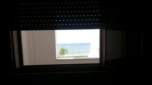 Una ventana con vista al mar y un árbol.