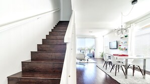 A staircase leading to a dining area with a white table and chairs, a television, and a window with blinds. - ★Sunny Condo 5min from the Beach★ (Laguna Niguel)