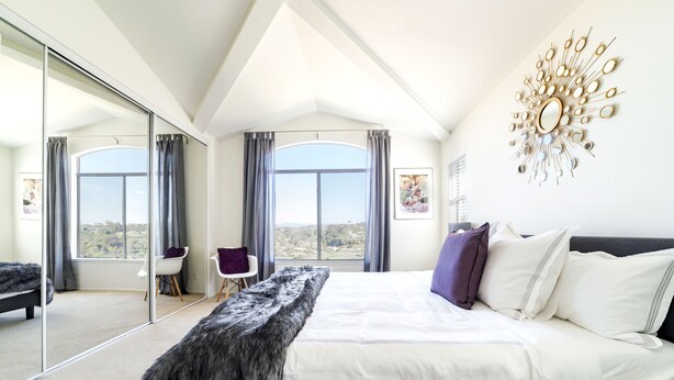 A modern bedroom with a large bed, a view through a sliding glass door, and a decorative wall piece. - ★Sunny Condo 5min from the Beach★ (Laguna Niguel)