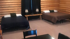 A log cabin room with two beds, a table, and chairs. - Cabin 5 (Garden City)