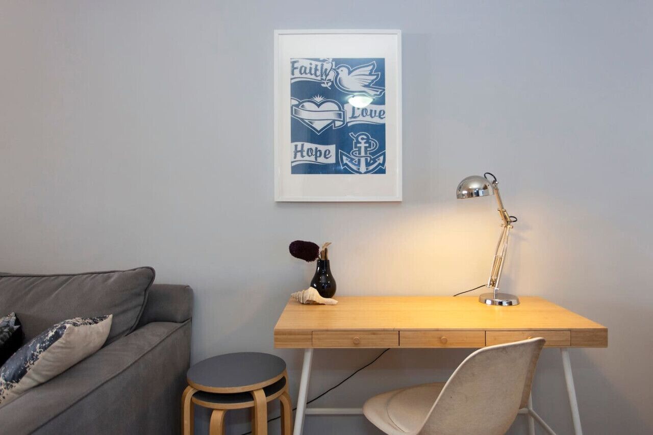 Een werkplek met een bureau, stoel en een geïnspireerd poster in een lijst aan de muur.
