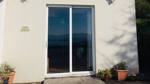 A two-story building with a large sliding glass door and two windows. - Harbour View Snug Apartment | Spectacular Sea Views | Sleeps 2–4 (Caherdaniel)