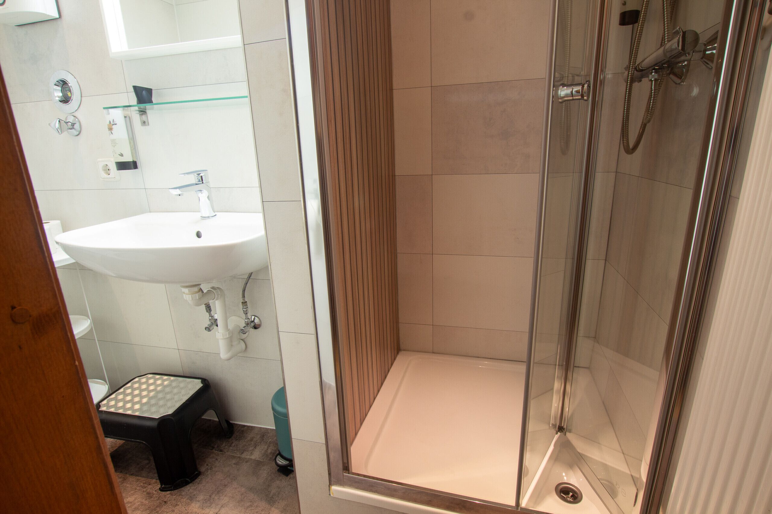 Een badkamer met een wastafel, spiegel en douche.