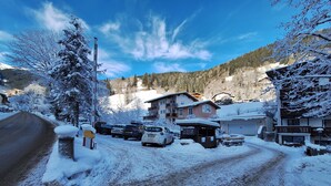 A snow-covered road with parked cars and buildings in the background. - Apartment Peacock, nahe Zentrum, am Skiweg (Zell am See)