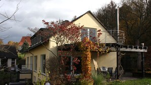 A two-story house with a balcony, surrounded by a garden with autumn foliage. - OWL's Nest with a view over Detmold (Klüt)