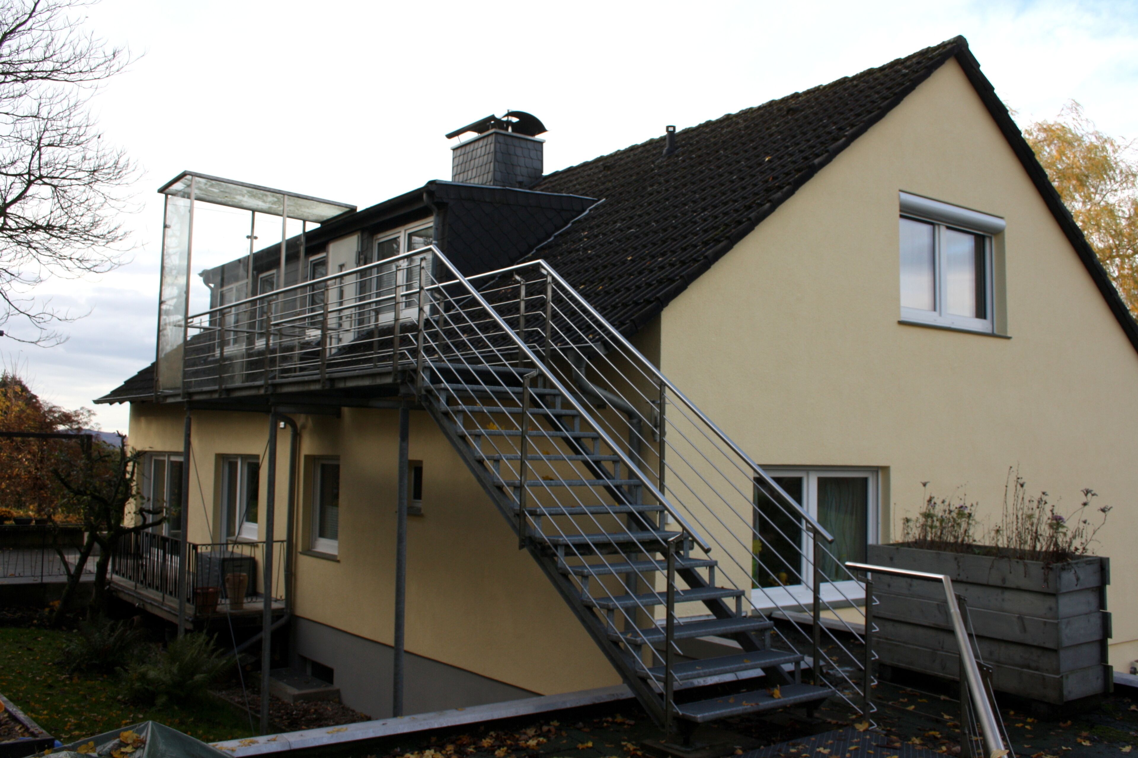 A two-story house with a metal staircase leading to a balcony.