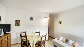 A compact living space with a dining area, a sofa, and a television.