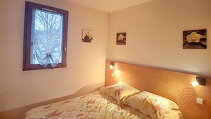 A bedroom with a bed, a window, and wall-mounted light fixtures.