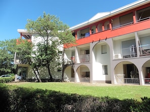 A multi-story building with balconies, arched windows, and a well-maintained lawn. - Charming Apartment with Terrace in Scenic Lamalou-les-Bains, Close to Town and Thermal Spa (Lamalou-les-Bains)