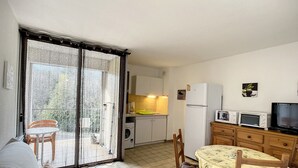 A compact kitchen with a dining area, a sofa, and a sliding glass door leading to an outdoor patio.