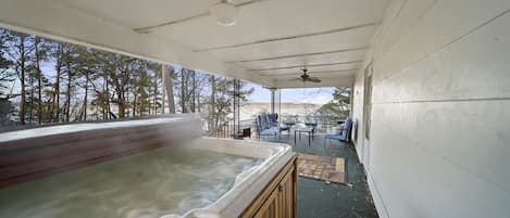 Ett bubbelbad på en inglasad veranda med utsikt över träd och ett avlägset landskap.