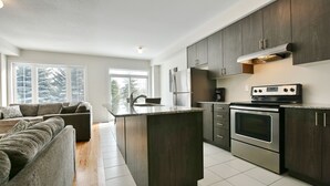 A modern kitchen with dark wood cabinets, stainless steel appliances, and a central island.