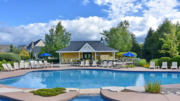 A swimming pool with lounge chairs and a building with a sign that reads "SHELL WATER NO DIVING".