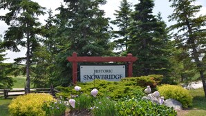 A sign for Historic Snowbridge with a garden in front.