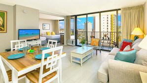 Una sala de estar moderna con comedor, televisor y balcón con vistas a la ciudad.