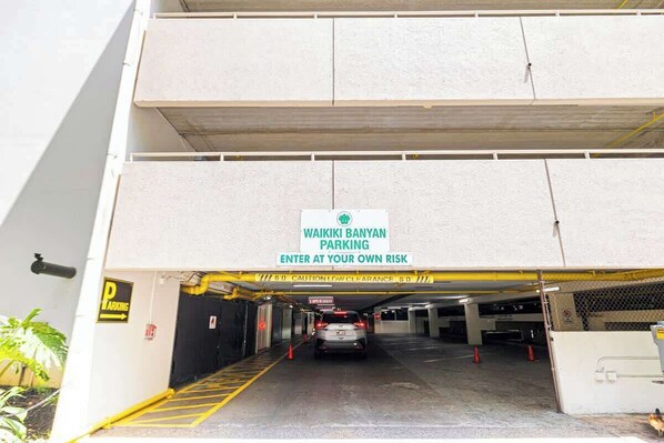 A parking garage entrance with a sign indicating 'WAIKIKI BANYAN PARKING' and a caution for 'LOW CLEARANCE.'