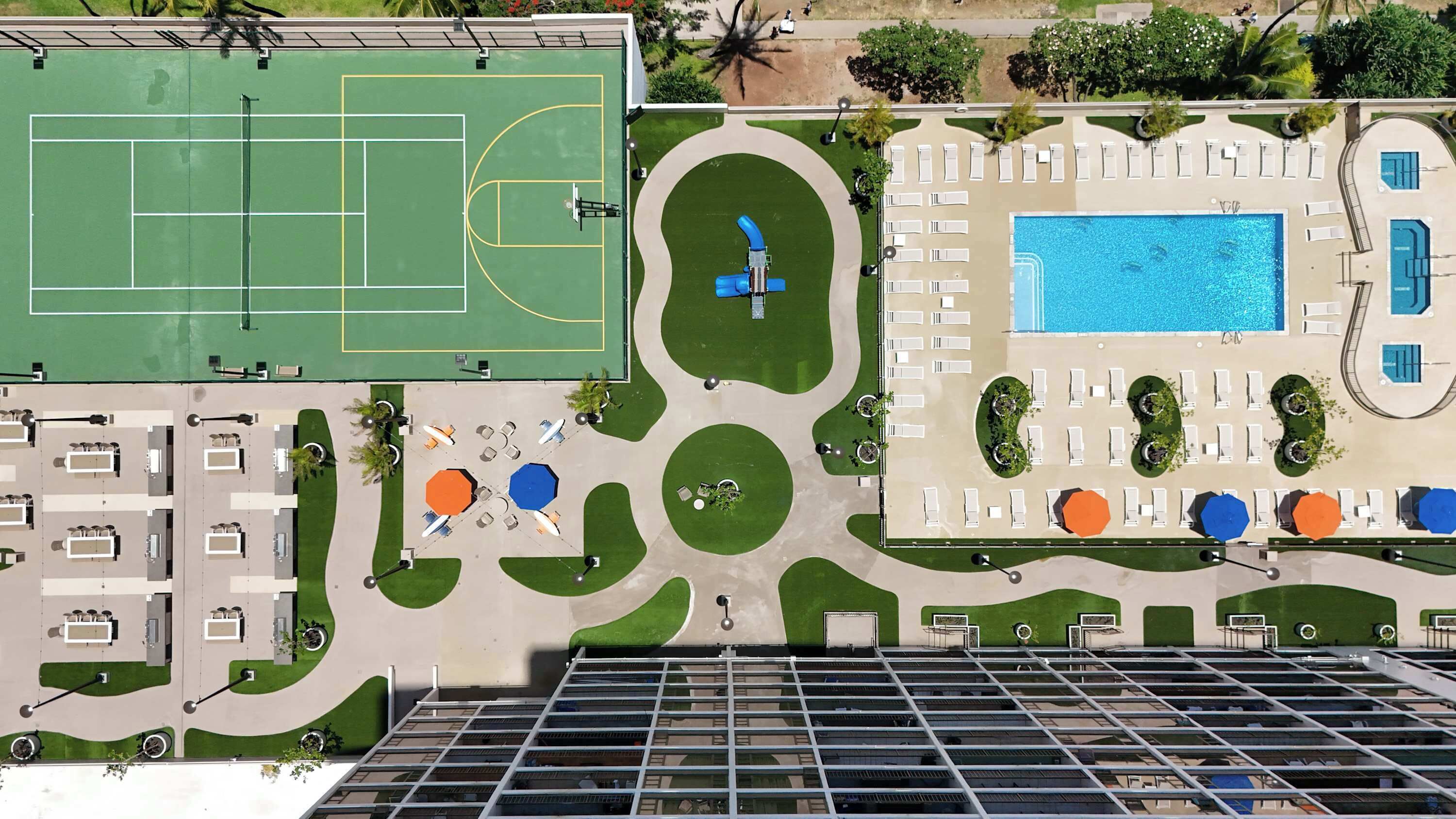 An aerial view of a hotel with a tennis court, swimming pool, and outdoor seating areas.