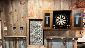 A room with a wooden wall, a dartboard, and a door with a decorative glass panel.