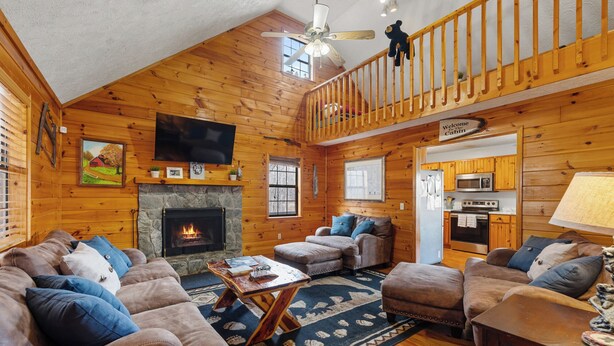 Un intérieur de chalet chaleureux avec une cheminée, des canapés en cuir, un coin repas et une cuisine.