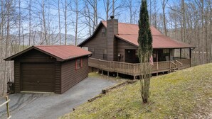 Une cabane rustique avec une façade en bois, une véranda et un garage.