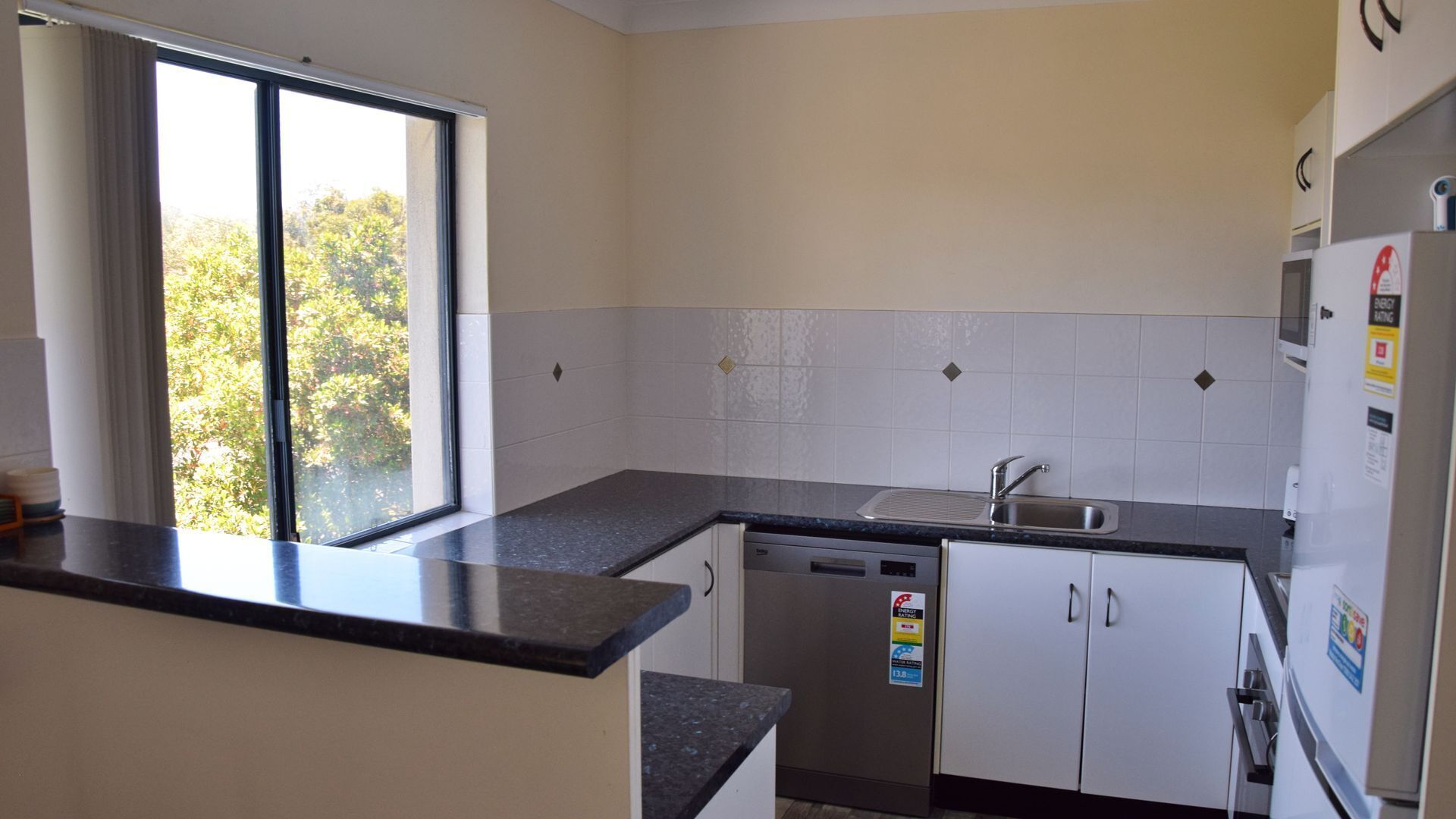 A compact kitchen with a window, a dishwasher, and a refrigerator.