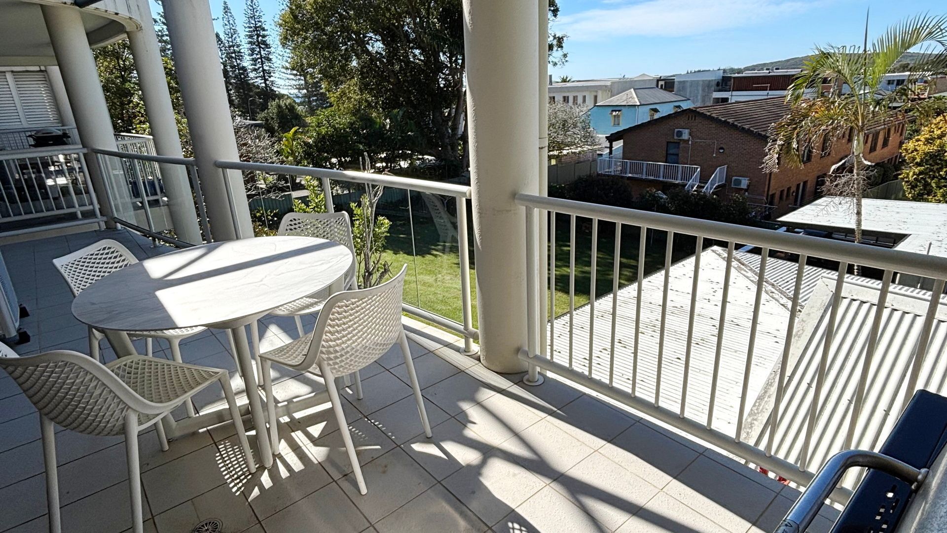A balcony with a table and chairs, a view of the neighborhood, and a railing.