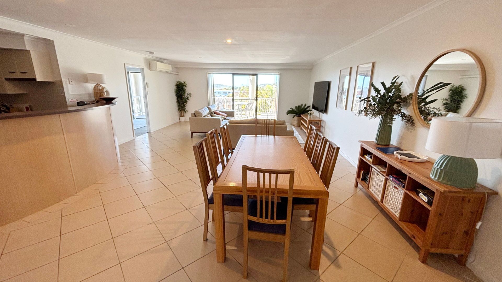Un grand espace de vie comprenant un coin repas avec une table et des chaises, un canapé et un coin cuisine avec un comptoir et des placards.