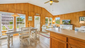 A spacious kitchen with wooden paneling, a dining area with white chairs, and a large island.