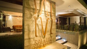 Ein moderner Hotelaufgang mit einem auffälligen Schild mit der Aufschrift "SAL & LUZ" und einer Steinwand.