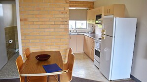 A compact kitchen with a brick wall, a sink, a stove, and a refrigerator.