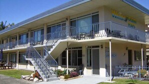 A two-story motel with a balcony on the second floor, a staircase leading to the entrance, and a 'No Vacancy' sign.