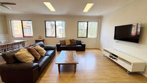 A spacious living room with a sofa, coffee table, and a TV mounted on the wall.