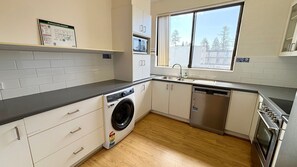 A modern kitchen with a washing machine, dishwasher, and stainless steel appliances.
