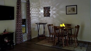 A dining area with a table and chairs, a flat-screen TV mounted on the wall, and a framed picture.