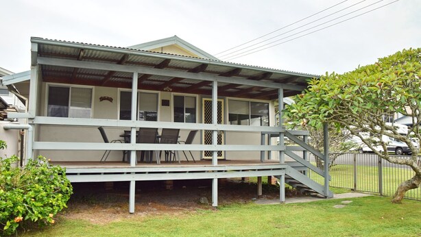 A two-story house with a covered porch, a staircase leading to the upper floor, and a fenced yard. - Sunshine Cottage - walk to the beach - Bring your own linen (SOUTH WEST ROCKS)