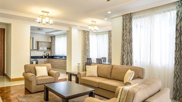 Ein geräumiges Wohnzimmer mit einer Sofagarnitur, einem Couchtisch und einer Küche im Hintergrund.