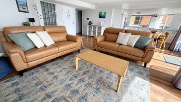 A modern living room with two leather sofas, a wooden coffee table, and a patterned rug.