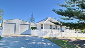 A two-story house with a garage, a covered porch, and a fenced yard. - Joanna Cottage - walk to the beach (SOUTH WEST ROCKS)