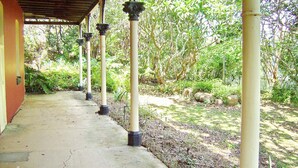 A covered walkway with columns, surrounded by greenery and trees.