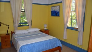 A bedroom with a bed, nightstands, a lamp, and a painting on the wall.