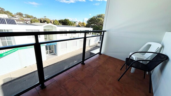 A balcony with a view of a street, a chair, and a sign for 'The Avenues'.