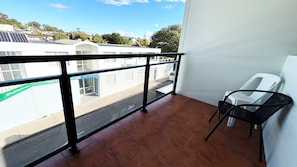 Ein Balkon mit Blick auf eine Straße, ein Stuhl und ein Schild mit der Aufschrift 'The Avenues'.