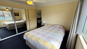 A hotel room with a large bed, a sliding door leading to a balcony, a ceiling fan, and a window with curtains. - Wenlaw Cottage (Rear) Hat Head (HAT HEAD)